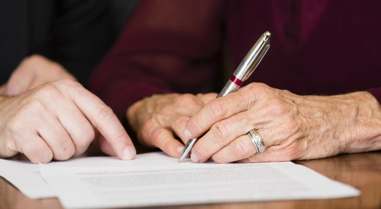 starsza kobieta podpisująca dokumenty